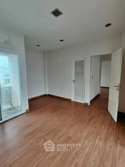 Spacious empty room with wooden flooring and white walls, ideal for customization.