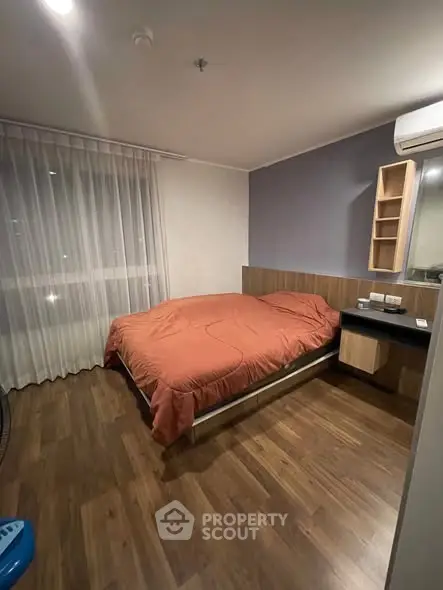 Cozy bedroom with wooden flooring and modern furnishings in a stylish apartment.