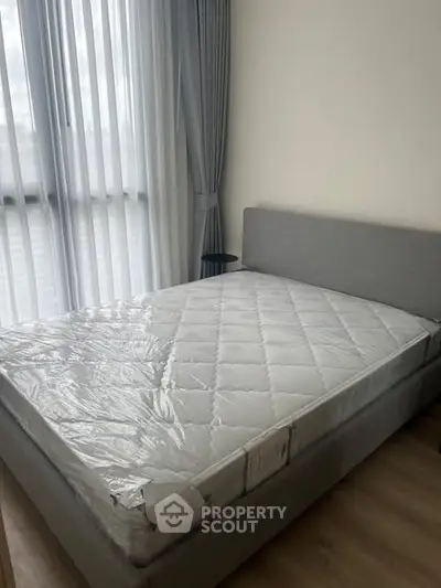 Modern bedroom with large window and stylish gray bed frame.