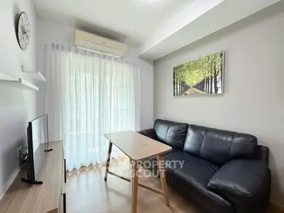 Cozy living room with black leather sofa and natural light