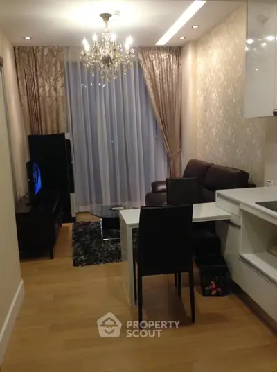 Elegant living room with chandelier, floor-to-ceiling curtains, and modern furniture in a cozy apartment.