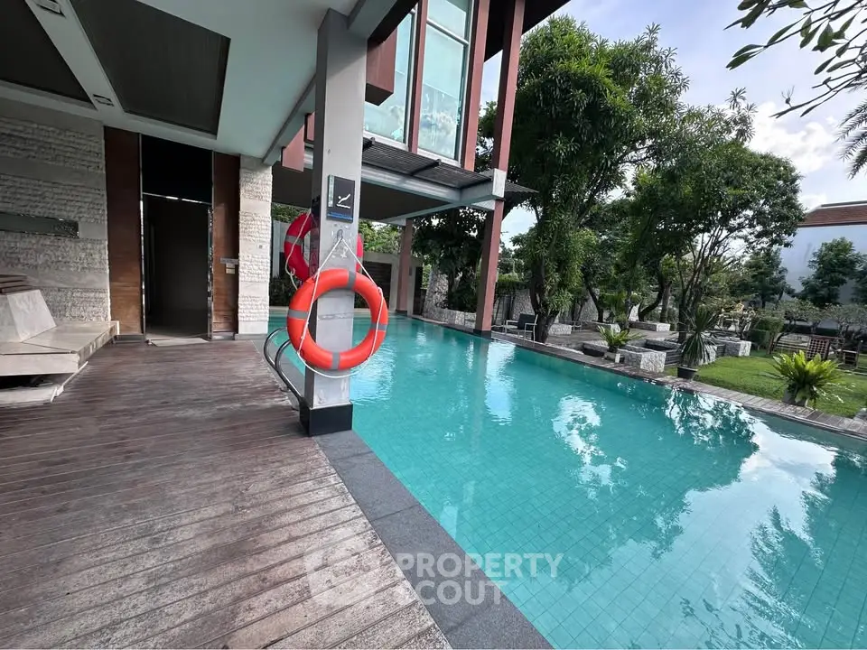 Luxurious modern poolside area with lush greenery and stylish architecture.