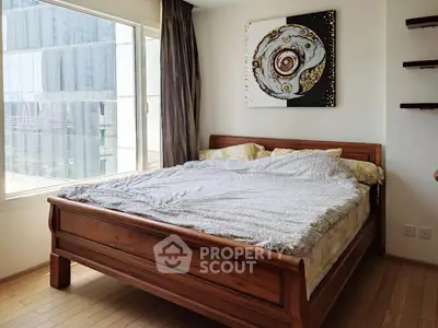 Cozy bedroom with wooden bed and large window offering city views