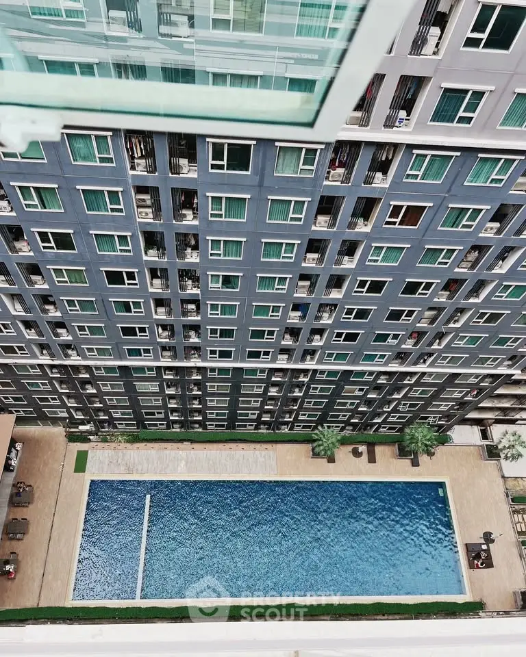 Stunning aerial view of modern apartment building with luxurious swimming pool.