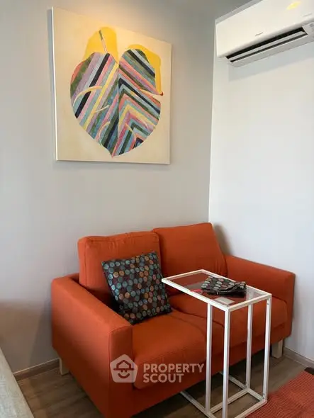Cozy living room with vibrant orange sofa and modern wall art, perfect for relaxation.