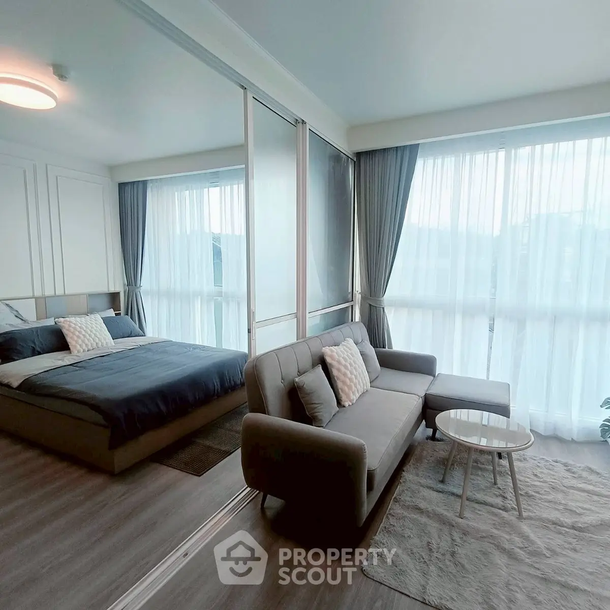 Modern bedroom with cozy seating area and large windows for natural light