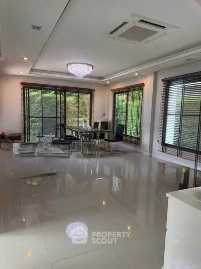 Spacious modern living room with elegant dining area and large windows offering lush garden views.