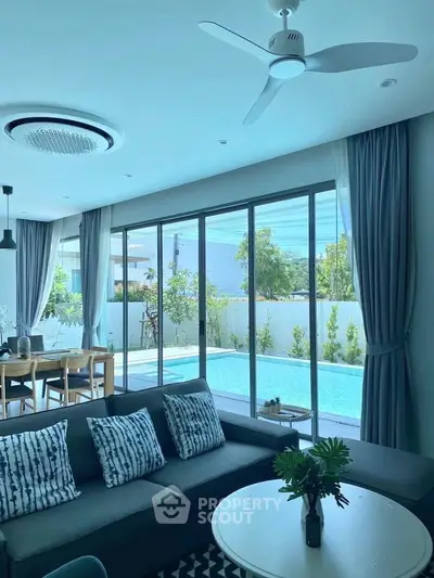 Luxurious living room with pool view, modern decor, and abundant natural light.