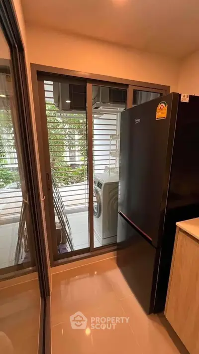 Modern kitchen with sleek black fridge and outdoor laundry view
