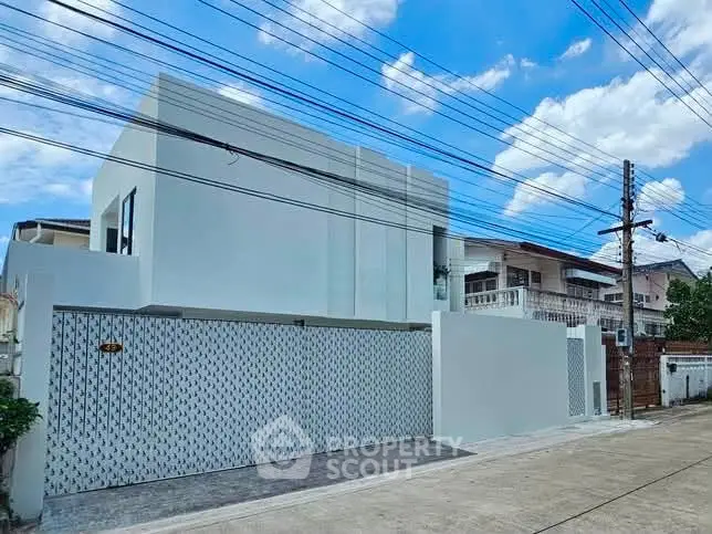 Modern minimalist white house exterior with clean lines and spacious driveway in a suburban neighborhood.