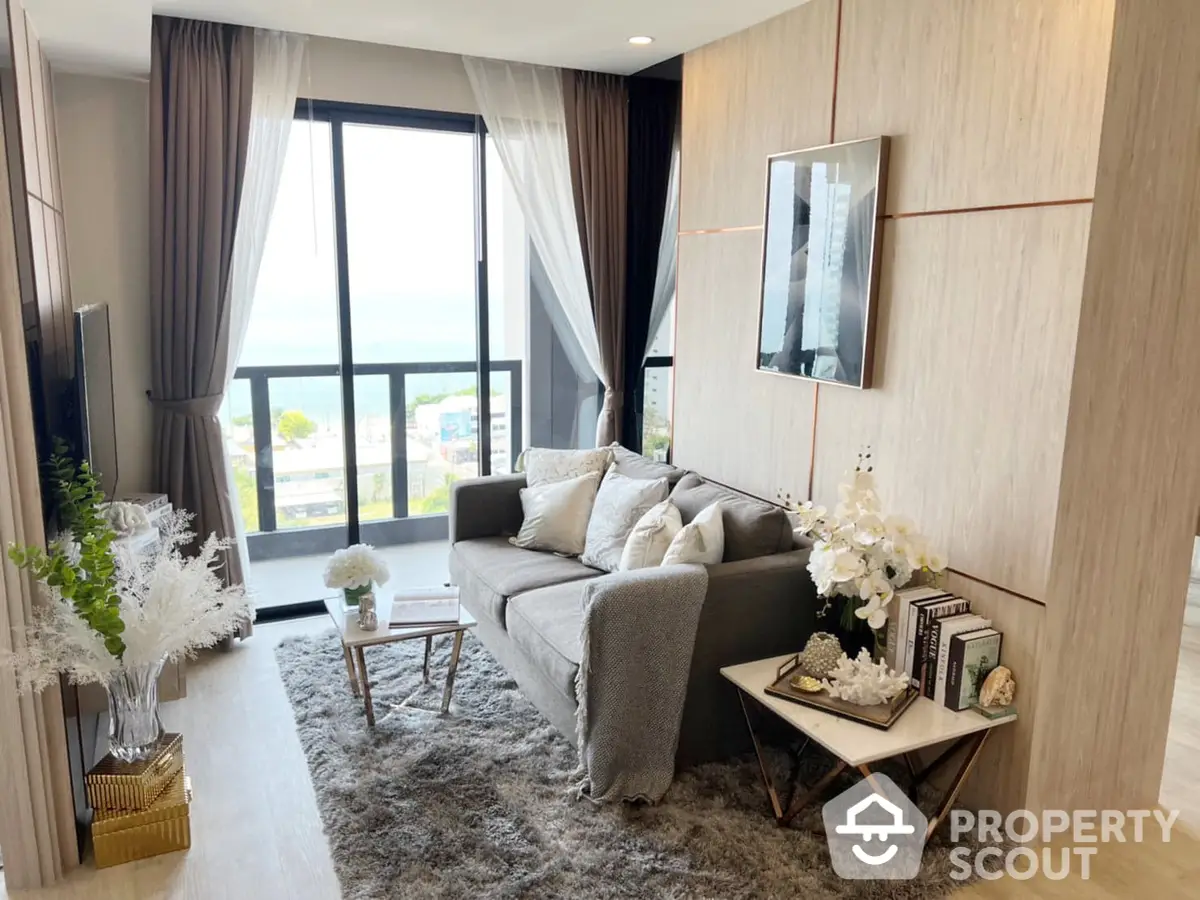 Elegant living room with plush grey sofa, chic decor, and floor-to-ceiling windows offering a luminous ambiance and a serene view.