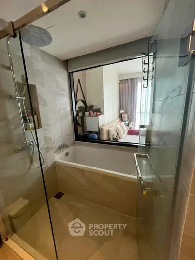 Modern bathroom with glass shower and bathtub overlooking a stylish living area.
