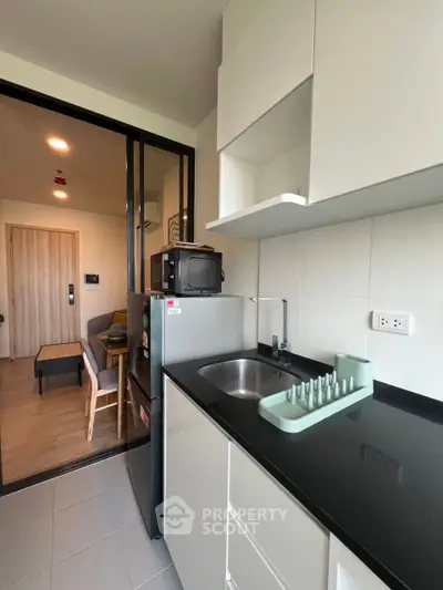 Modern compact kitchen with sleek black countertop and open layout to living area