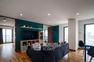 Spacious modern living room with wooden flooring and city view, perfect for urban living.