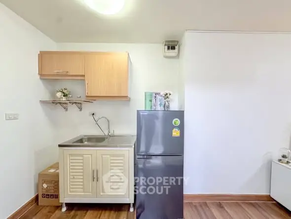 Compact kitchen with modern fridge and wooden cabinets in cozy apartment