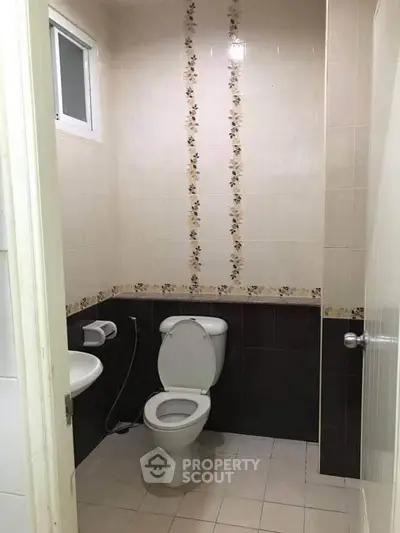 Compact bathroom with floral tile accents and modern fixtures.