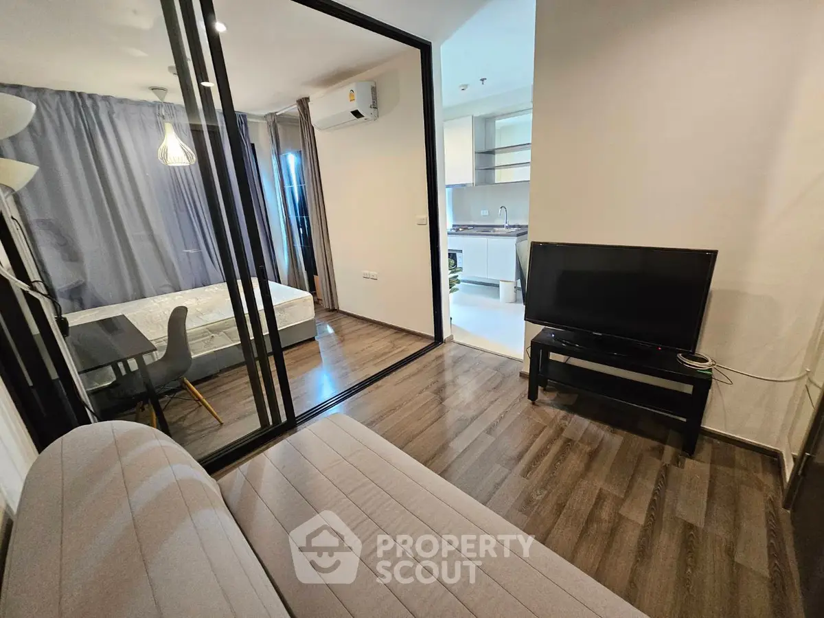 Modern apartment interior with open layout, featuring a cozy living room and adjacent bedroom.