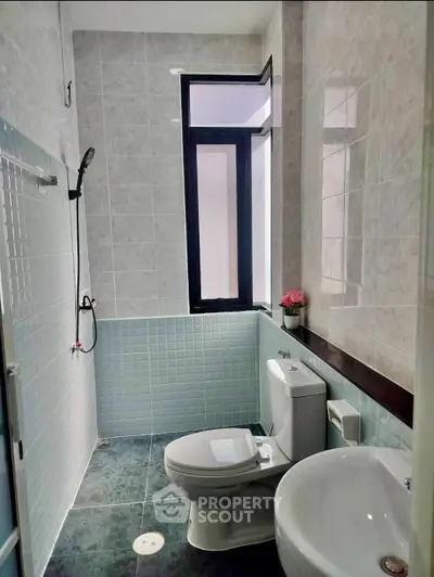Modern bathroom with sleek design, featuring a shower, toilet, and sink with natural light from a large window.