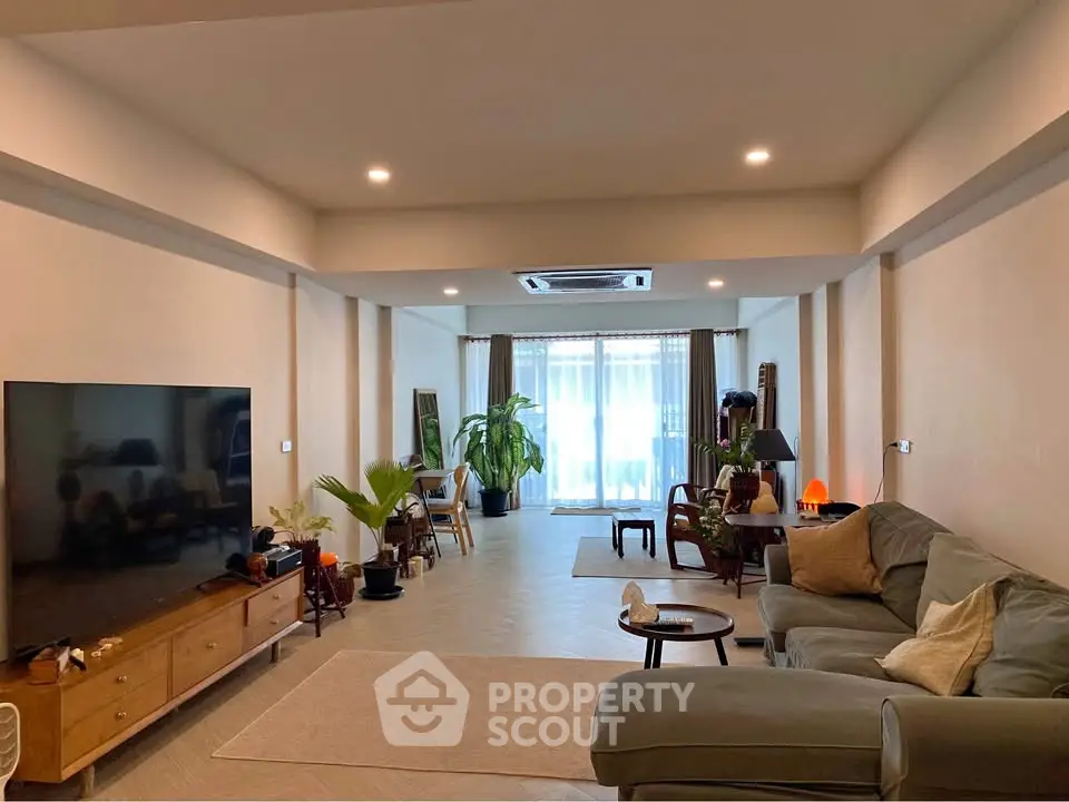 Spacious living room with modern decor and large TV, perfect for relaxation and entertainment.