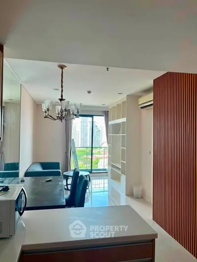 Modern living room with city view, elegant chandelier, and open layout for seamless living experience.