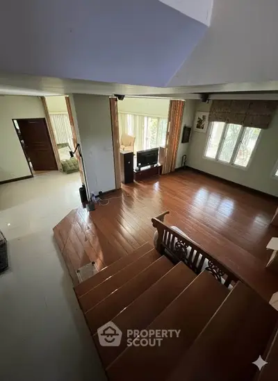Spacious living room with wooden flooring and large windows for natural light.