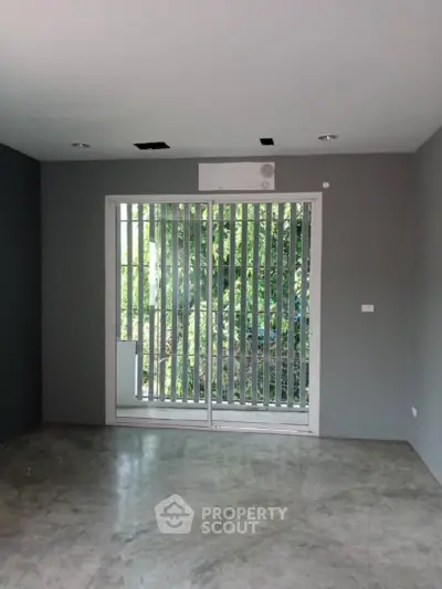 Spacious room with large window and garden view, ideal for customization.