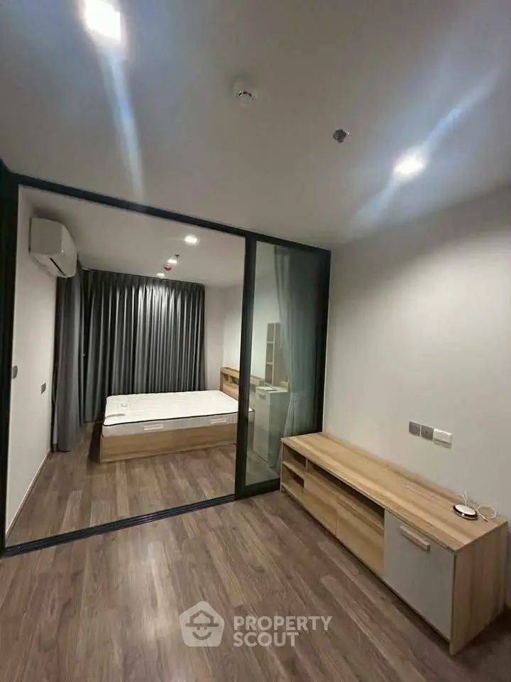 Modern bedroom with glass partition and wooden flooring in a stylish apartment.