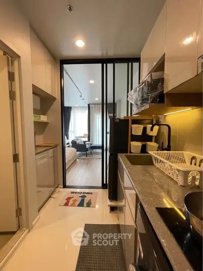 Modern apartment kitchen with sleek design and open layout leading to a cozy living area.
