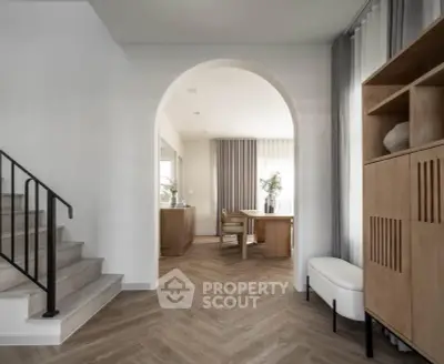Elegant modern interior with archway, stylish furniture, and herringbone flooring in a bright living space.