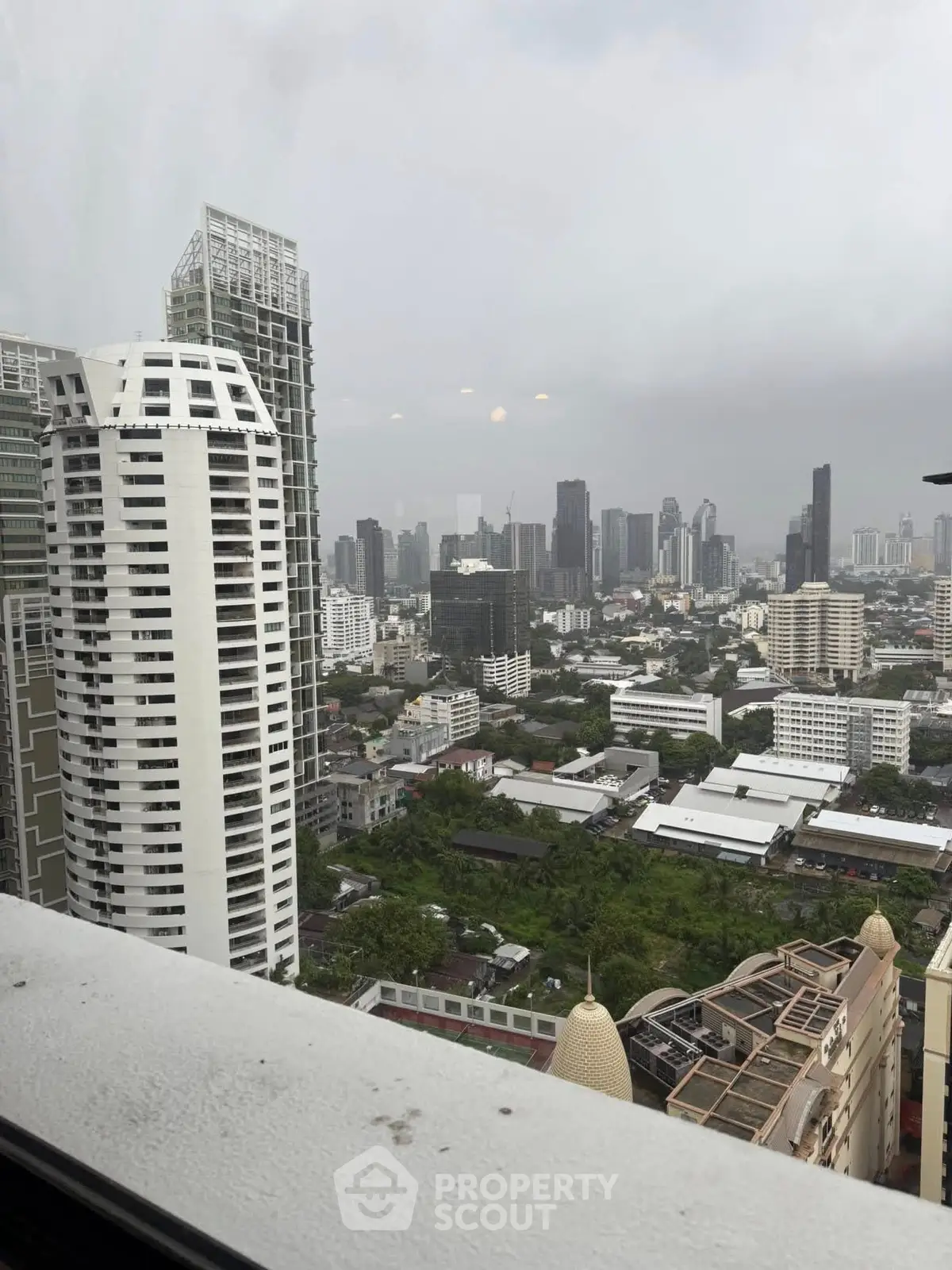 Stunning cityscape view from high-rise building showcasing urban skyline and lush greenery.