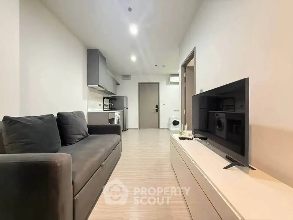 Modern living room with sleek furniture and integrated kitchen appliances in a cozy apartment.