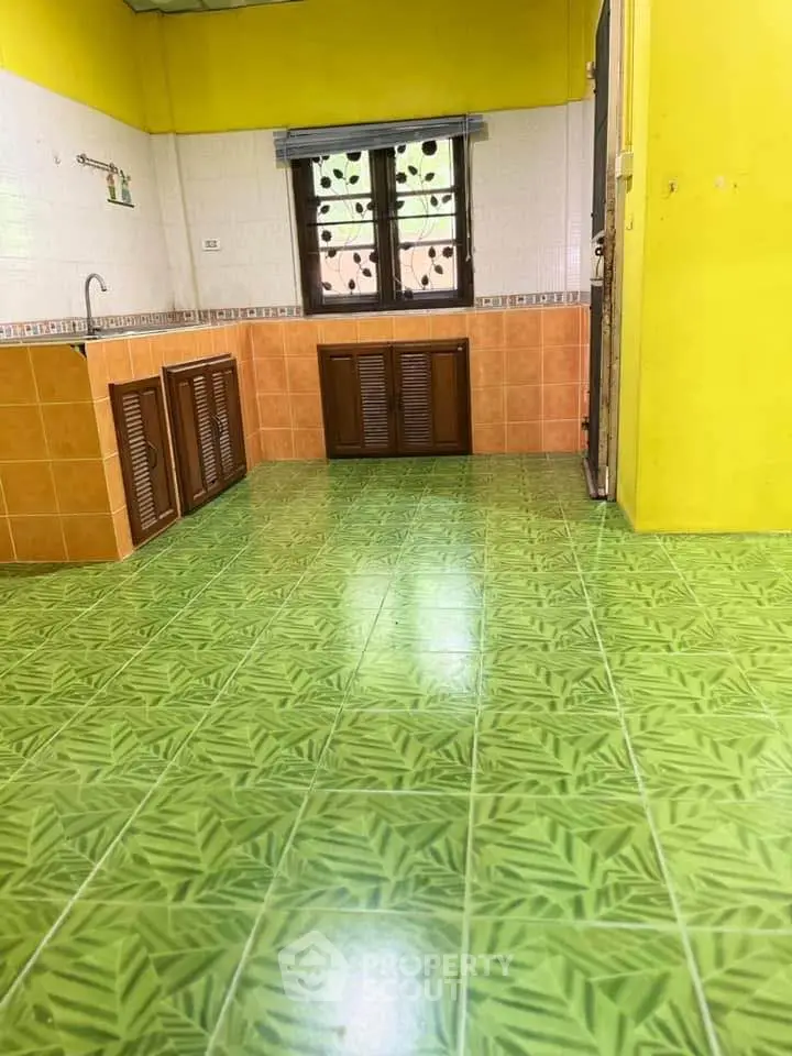 Charming kitchen with vibrant green tile flooring and rustic wooden cabinets.