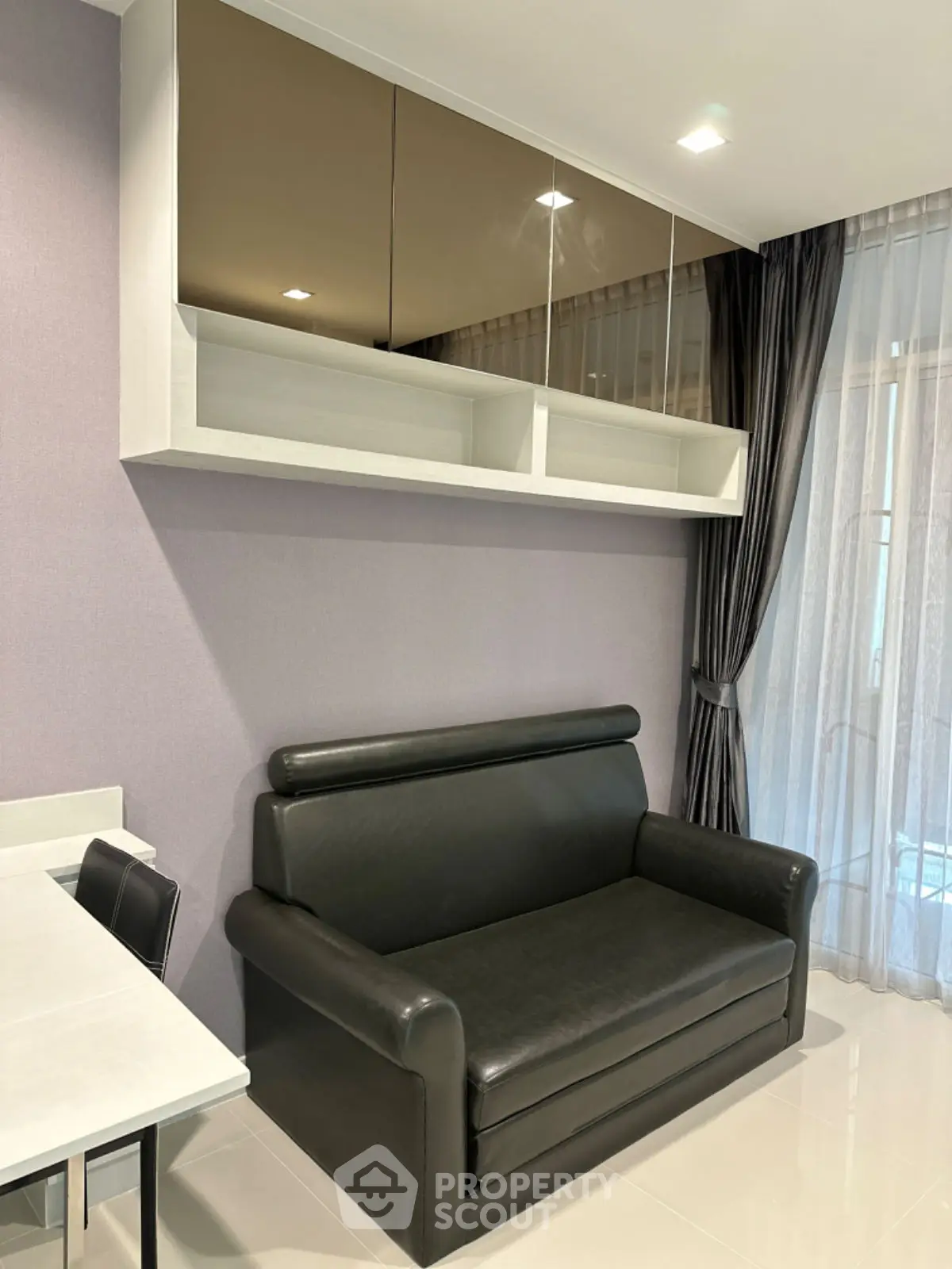 Modern living room with sleek black sofa and stylish wall-mounted storage.