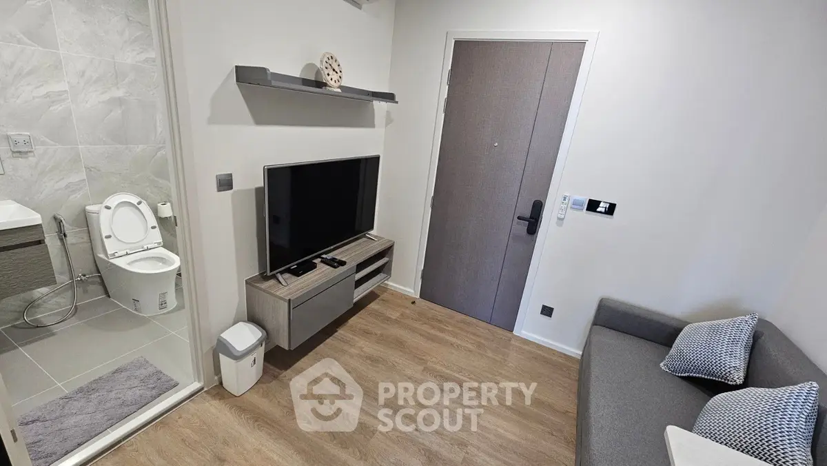 Modern compact living room with TV and adjacent bathroom in a cozy apartment.