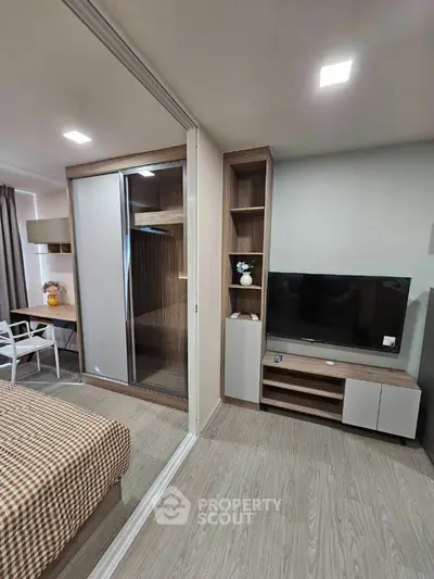 Modern bedroom with sliding wardrobe and TV unit in stylish apartment