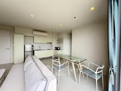 Modern open-layout living room with sleek kitchen and glass dining table