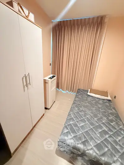 Cozy bedroom with single bed, wardrobe, and window with curtains in modern apartment.