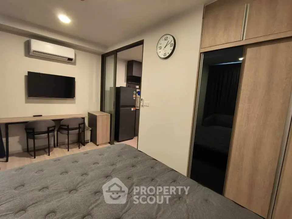 Modern bedroom with sleek furniture and wall-mounted TV, featuring a stylish wardrobe and air conditioning.