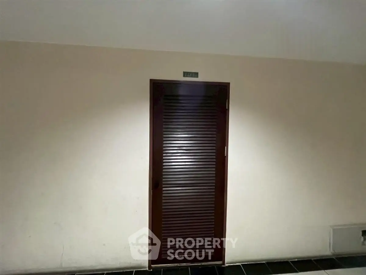 Dimly lit corridor with a closed wooden door, ideal for secure storage or utility access.