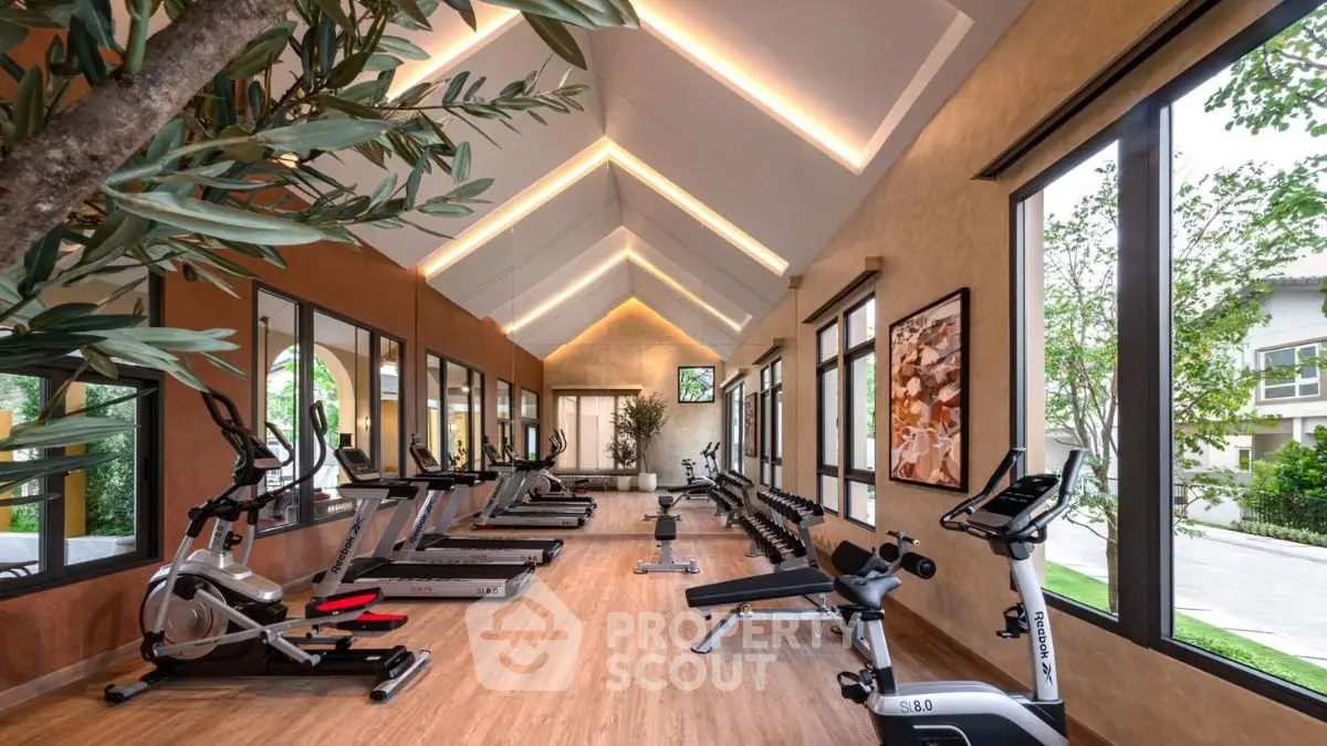 Spacious modern gym with state-of-the-art equipment and large windows for natural light.