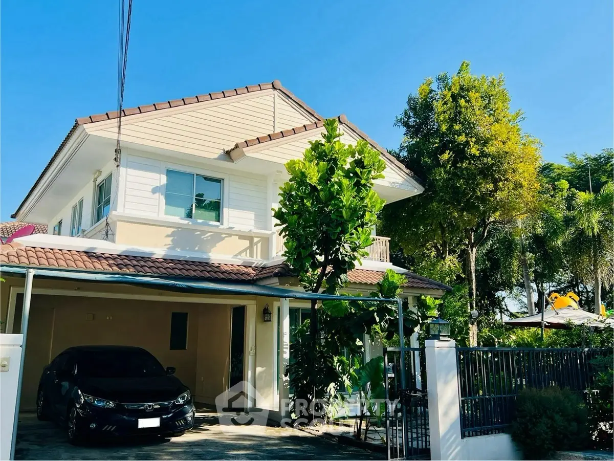 Charming two-story house with lush greenery and carport in a serene neighborhood.
