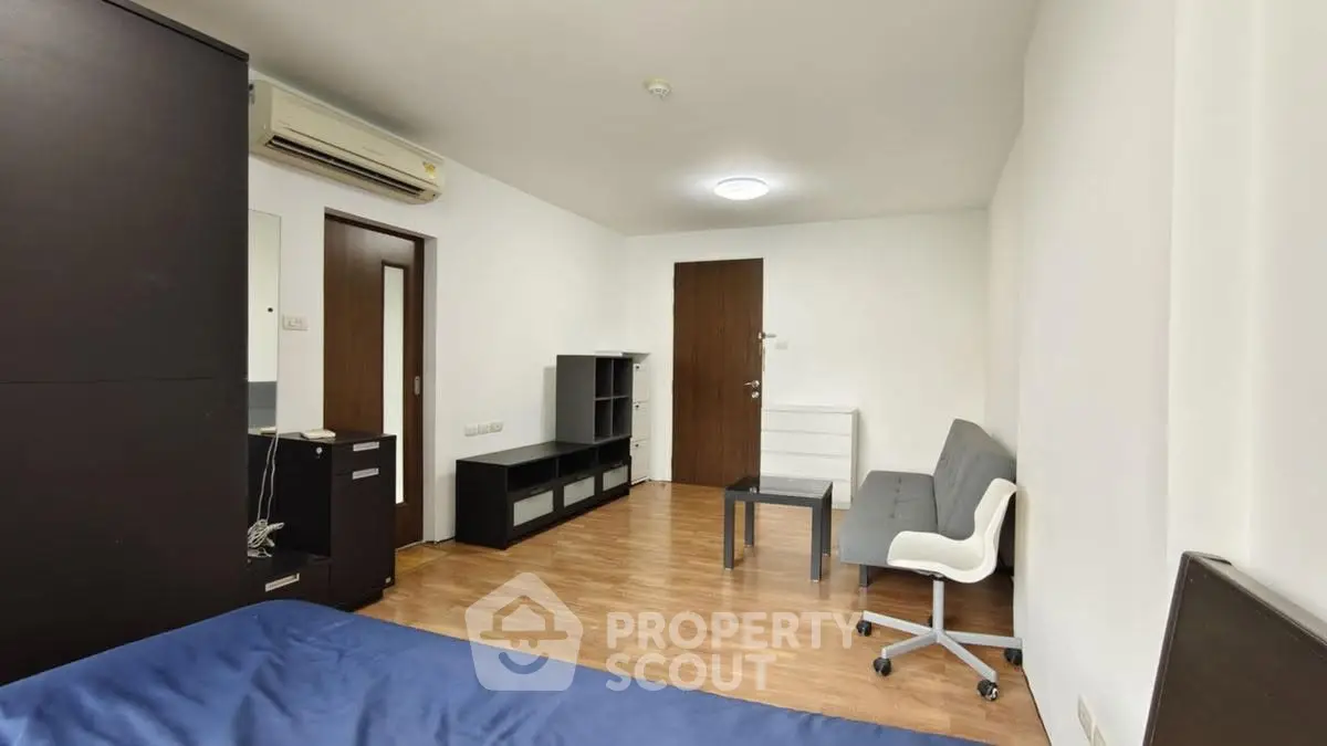 Spacious bedroom with modern furniture and wooden flooring in a minimalist apartment.