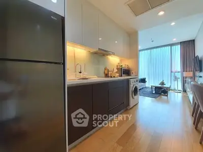 Modern kitchen with sleek appliances and open layout leading to living area.