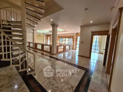 Luxurious open-plan living area with elegant staircase and marble flooring
