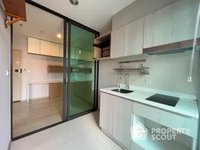 Modern kitchen with sleek cabinetry and glass sliding doors in contemporary apartment.