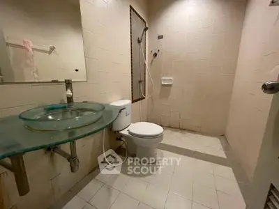 Modern bathroom with glass sink and shower area in a real estate property.