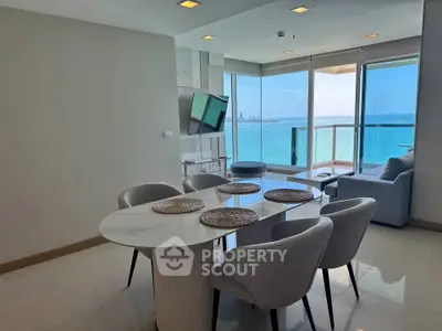 Stunning ocean-view living room with modern dining area and large windows.