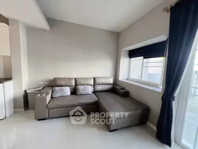 Modern living room with sleek gray sectional sofa and large window for natural light.