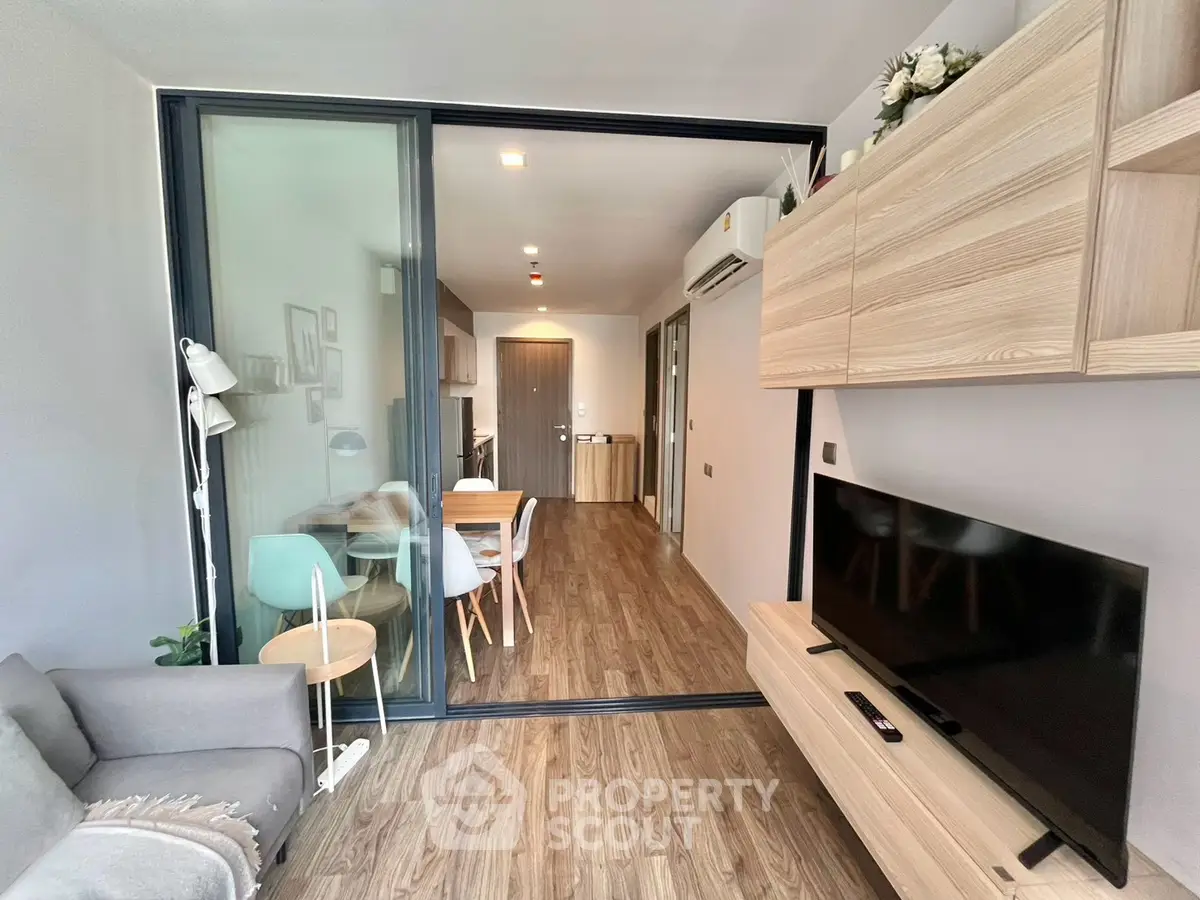 Modern living room with sliding glass doors, stylish furniture, and wooden flooring in a cozy apartment.
