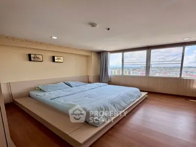 Spacious bedroom with large windows offering stunning city views, featuring a modern platform bed and wooden flooring.